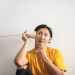 pensive ethnic man listening to answer in paper cup phone