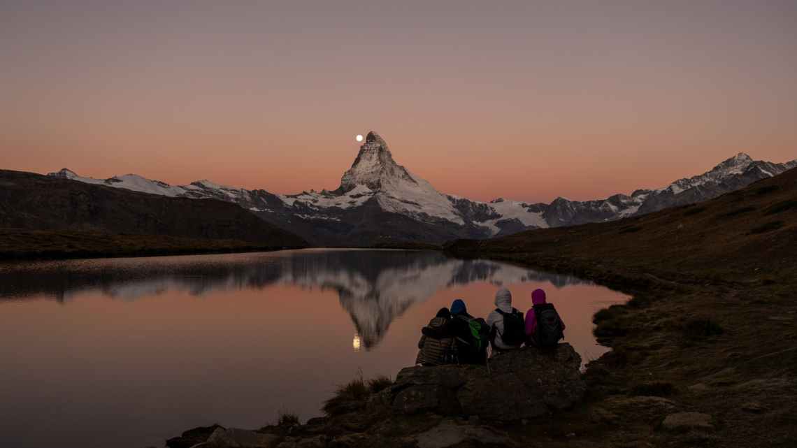 people sitting on rock near lake