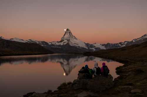 people sitting on rock near lake